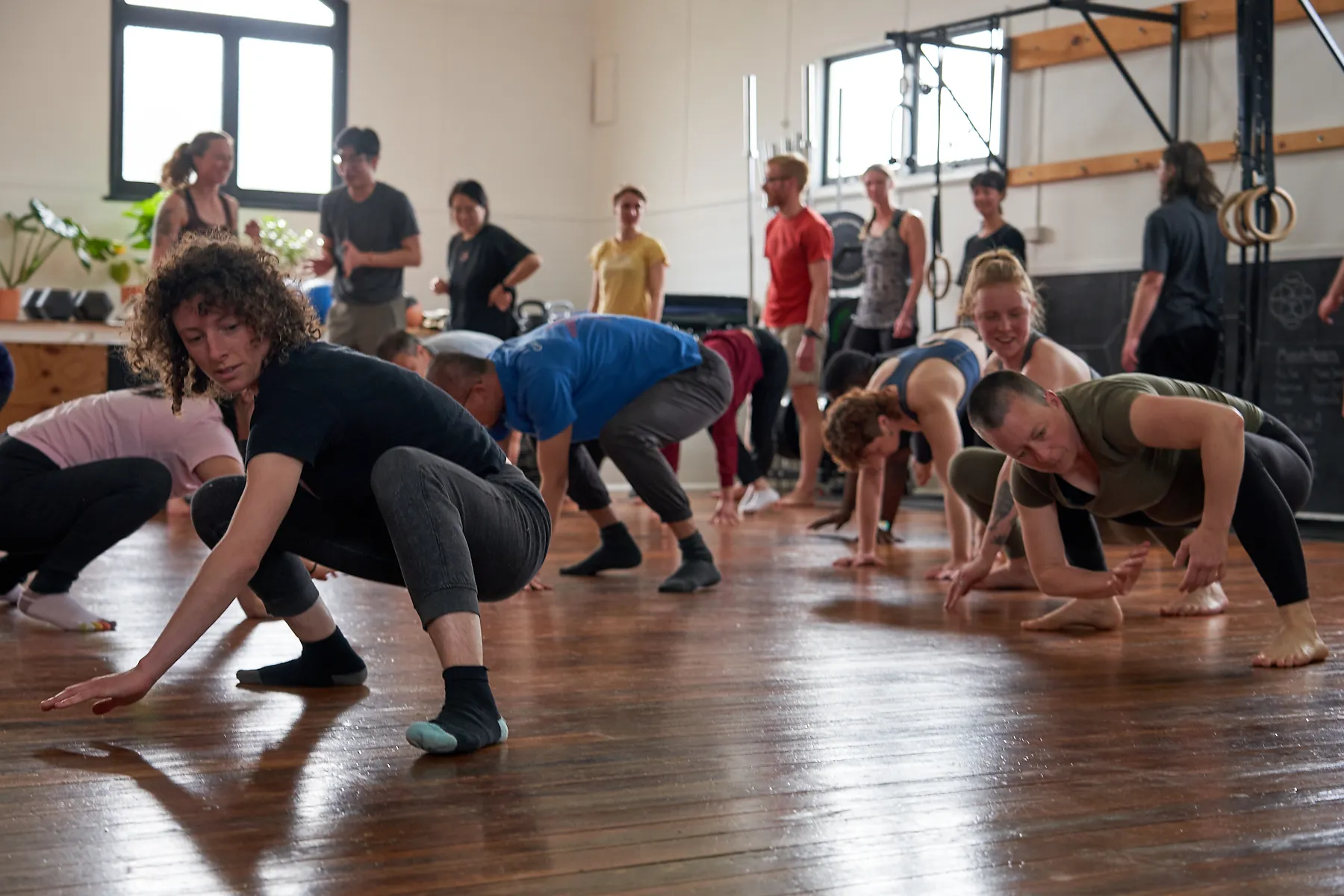 A full class of mixed ages travelling low across the wooden studio floor together